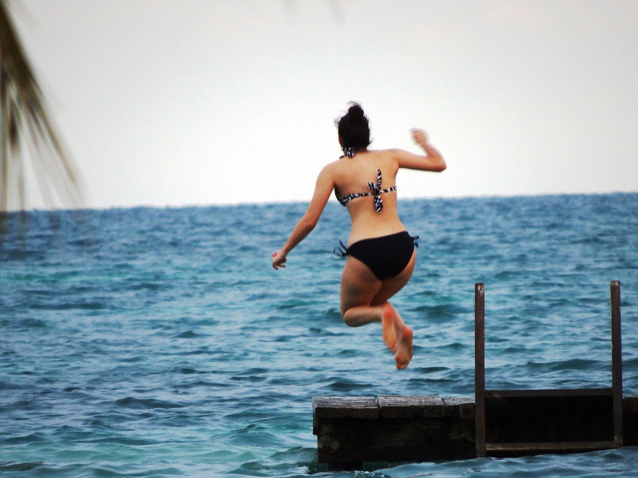 Guest jumping off dock at St George's Caye Resort Belize